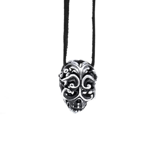 The Filigree Skull Pendant in sterling silver, its domed skull carved with scrolling filigree, hung on a black leather cord by Ether Eleven.